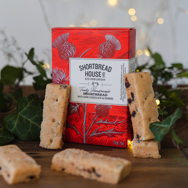 Red box of Shortbread House of Edinburgh shortbread with biscuits on a wooden surface.