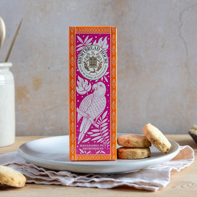Pink and Orange box of shortbread surrounded by biscuits and macadamia nuts