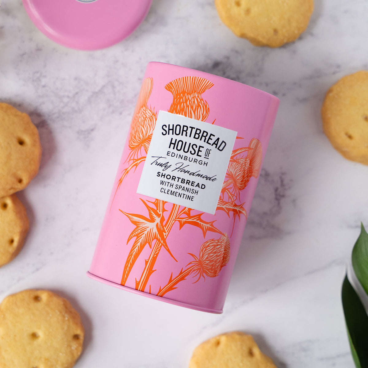 Pink Shortbread House tin with shortbread biscuits on a marble surface