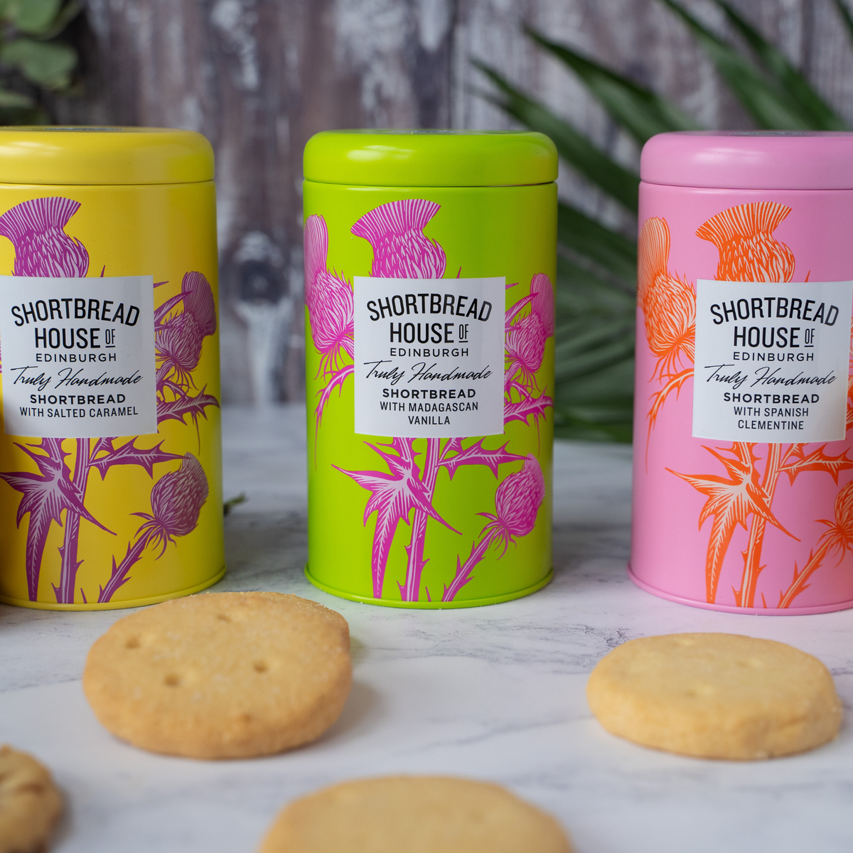 Three colorful tins of Shortbread House shortbread biscuits in front