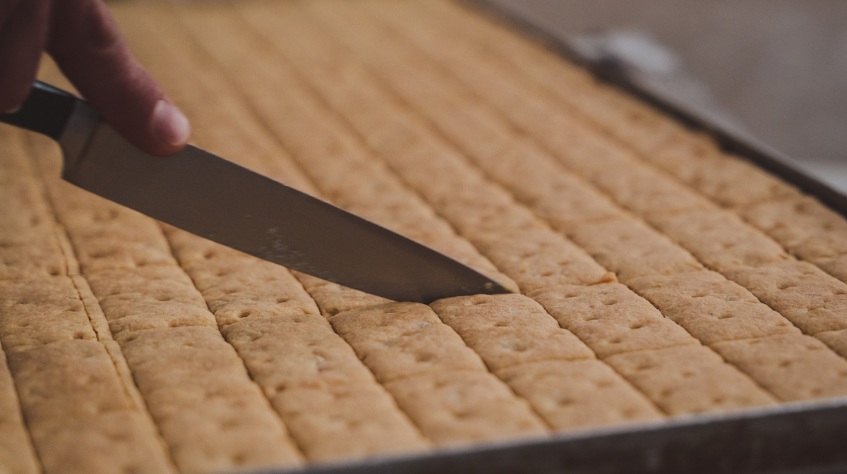 Hand using a knife to cut a tray of biscuits 