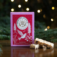 Red box of Shortbread Fingers with fir branches and lights in the background