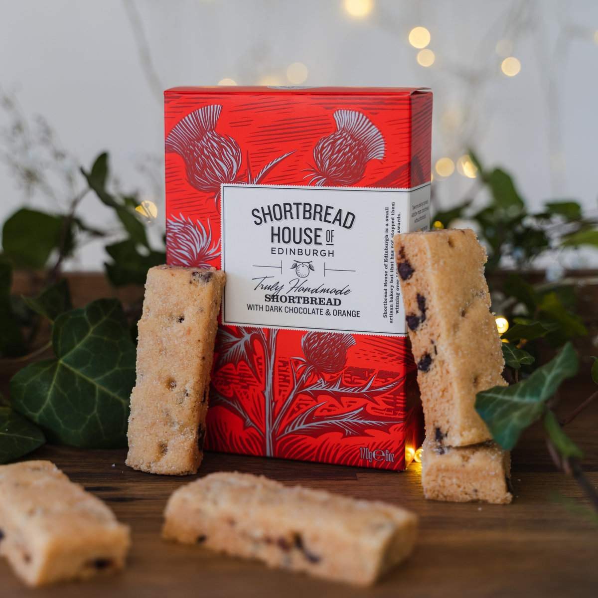 Red box of Shortbread House of Edinburgh shortbread with biscuits on a wooden surface.