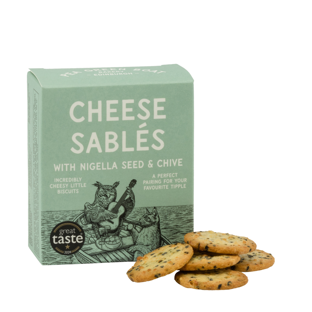 Small green box of Nigella Seed and Chive Cheese Sables with biscuits stacked to the side. 