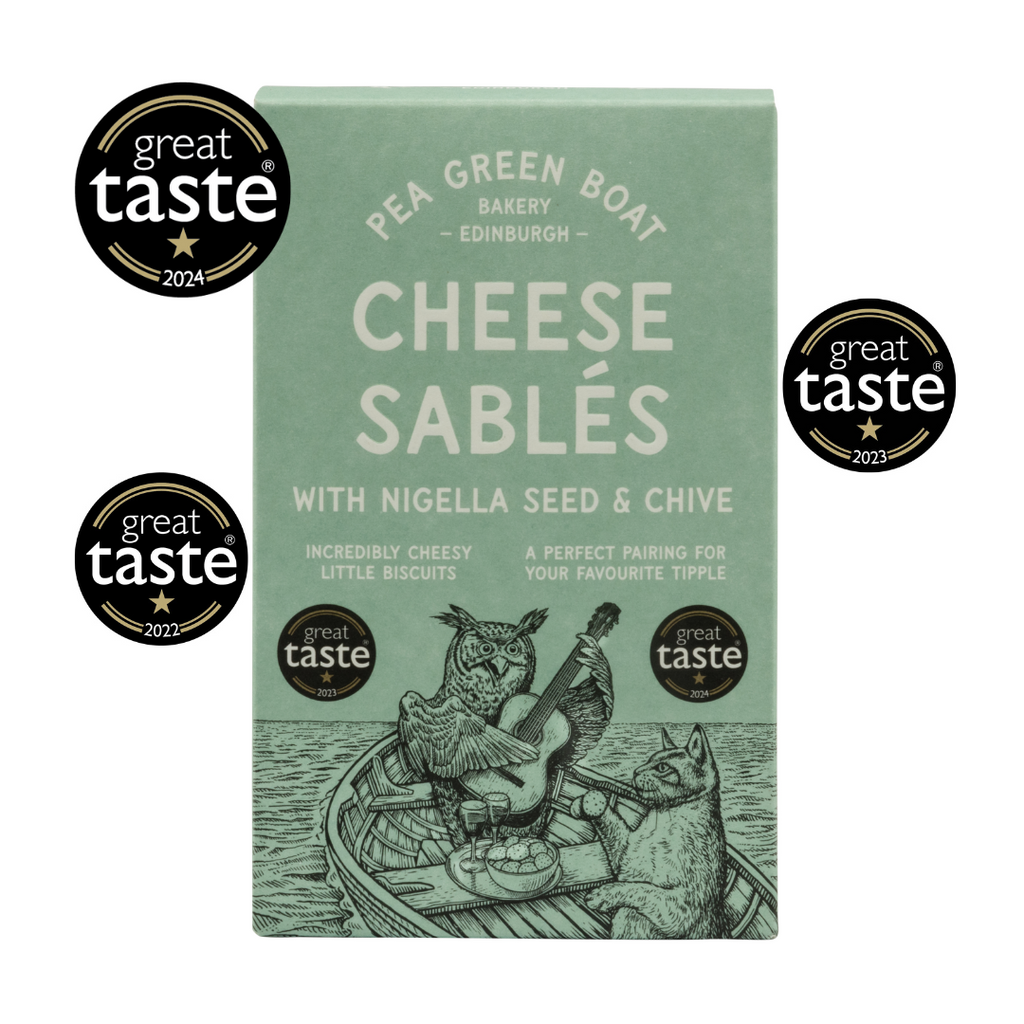 Green box of Nigella Seed and Chive Cheese Sables surrounded by 3 Great Taste Awards around it. 