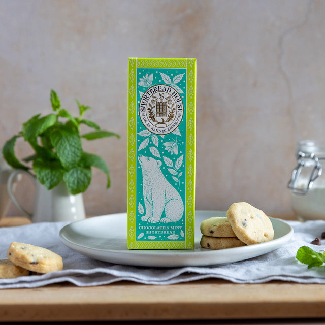 Box of chocolate and mint shortbread surrounded by biscuits and kitchen items