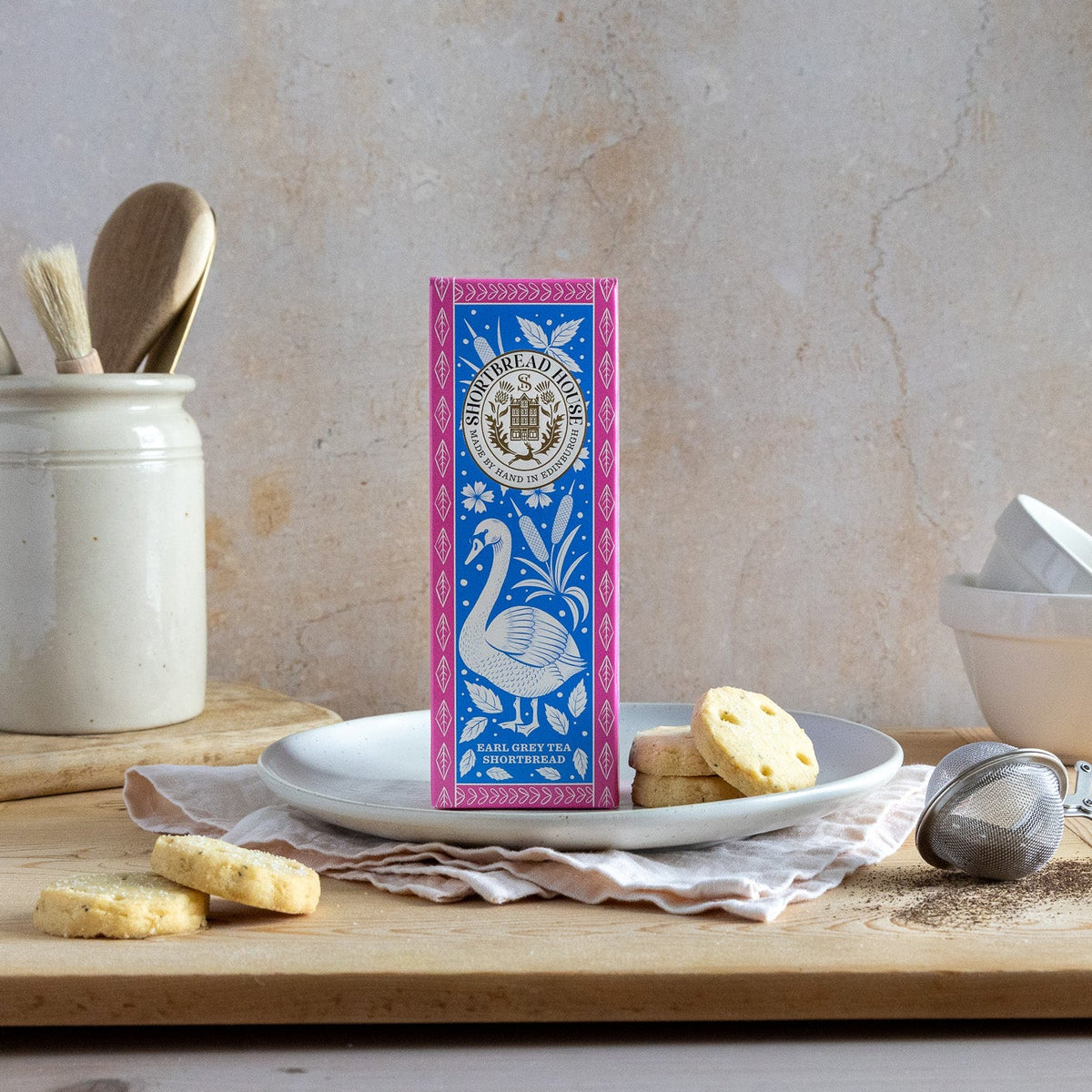 Shortbread box with decorative design on a kitchen counter with tea and cookies.