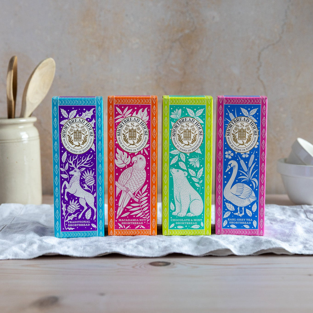 Four colorful tea boxes with animal illustrations on a wooden surface.