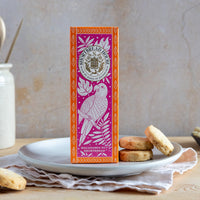 Pink and Orange box of shortbread surrounded by biscuits and macadamia nuts