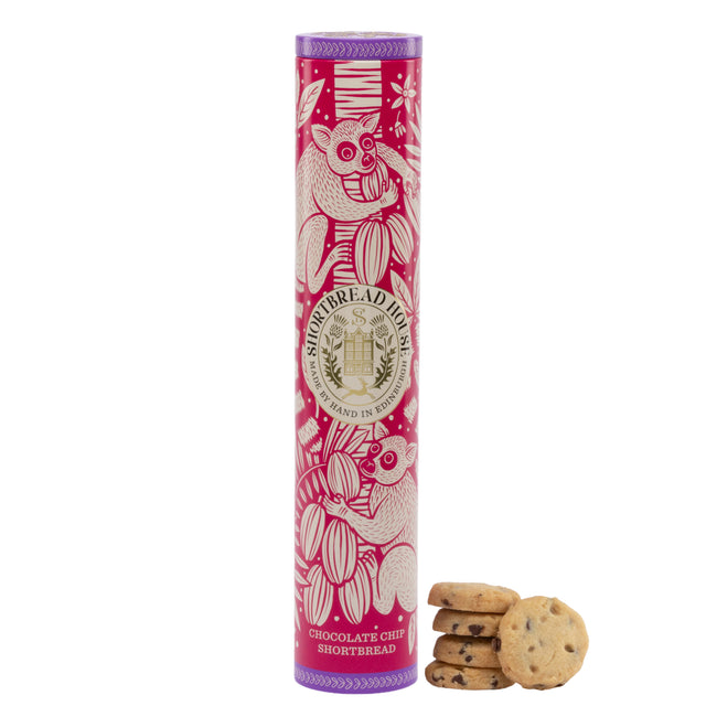 Cylindrical pink and purple shortbread tins next to some chocolate chip shortbread biscuits. The tin has illustrations of lemurs and foliage.