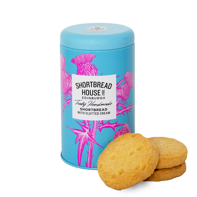 A blue cylindrical tin with a thistle pattern labeled 'Shortbread House of Edinburgh' alongside three handmade shortbread biscuits outside the tin.