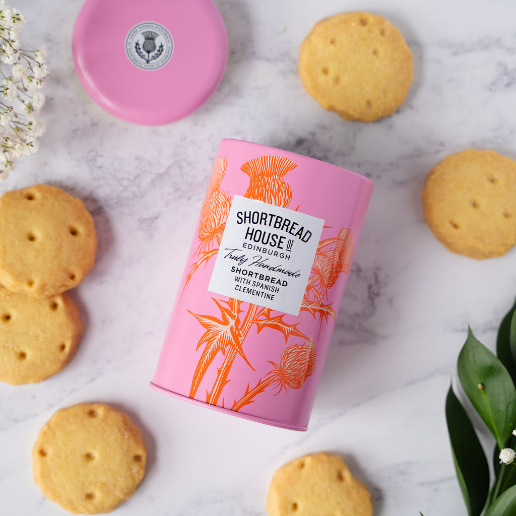 Pink Shortbread House tin with shortbread biscuits on a marble surface
